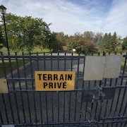 Une affiche indiquant un «terrain privé» est accrochée à une clôture qui empêche d'avoir accès au terrain de golf.