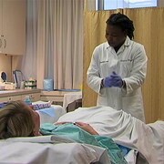 Une médecin devant une patiente couchée sur un lit d'hôpital.