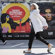 Des passantes circulent devant une affiche du Festival international du film de Toronto 2024.