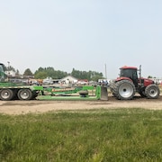 Un tracteur tire une charge sur une piste de terre.
