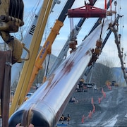 Un tuyau d'oléoduc suspendu dans les airs par des grues sur un chantier entre Hope et Chilliwack, en Colombie-Britannique.