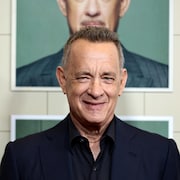 Un homme aux cheveux gris sourit.