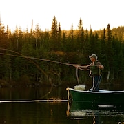 Un pêcheur lance un filet debout sur son canoé.