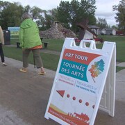 Une affiche de la tournée artistique avec des personnes marchant à l'arrière-plan le 16 septembre 2023 à Richer au Manitoba. 