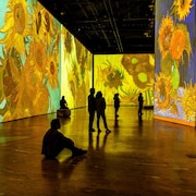 Des spectateurs dans une salle où sont projetées des toiles du peintre Vincent Van Gogh.