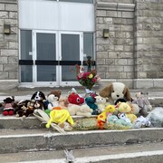 Des peluches et des fleurs sur le parvis de l'église.