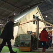 Des visiteurs déambulent devant une maison préfabriquée dans un centre d'exposition.