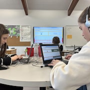 Des élèves pianotent sur les claviers d'ordinateurs portables dans une salle de classe. 
