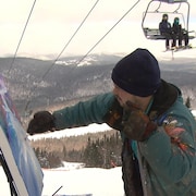 Samuel Gagnon peint au sommet d'une pente de ski sous le regard des curieux dans la remontée mécanique.