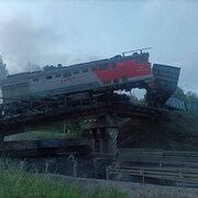 Un train est en partie suspendu après avoir déraillé sur un pont qui s'est effondré.