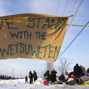Une banderole avec le message We Stand With The Wet'suwet'en flotte au vent.