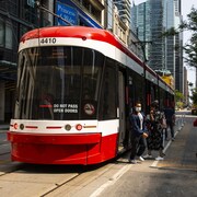Des usagers descendent du tramway sur la rue King au centre-ville de Toronto.