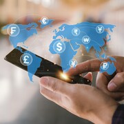 Homme tenant un smartphone pour effectuer des transactions financières en ligne pour des dépenses à l'étranger. Travail sur le marché financier mondial via un appareil mobile. Transfert et échange d'argent, concepts de devises mondiales.