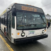 Un autobus de la Ville de Rouyn-Noranda se stationne près d'un trottoir lors d'une journée pluvieuse. 