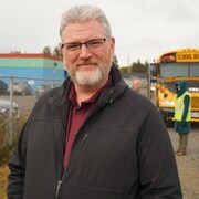 Craig Murphy devant un autobus scolaire.