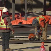 Deux travailleurs portant des vestes de sécurité sur un chantier de construction.