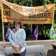 Annick Charette, présidente de la FNCC–CSN, devant une banderole