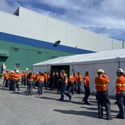 Des travailleurs discutent à l'extérieur de l'usine.