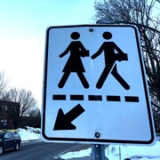 Photographie en contre-plongée d’un panneau de signalisation annonçant une traverse pour écoliers.