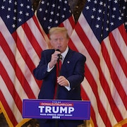 Donald Trump devant des drapeaux américains. 