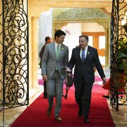 Justin Trudeau et François Legault en train de marcher dans un corridor en discutant. 