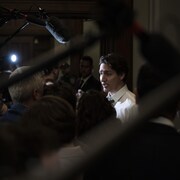 Monsieur Trudeau entouré de journalistes et de micros.