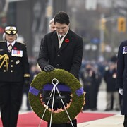 Un homme dépose une couronne de fleurs devant des vétérans et la gouverneure générale.