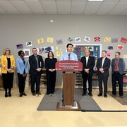 Justin Trudeau parle devant un micro avec des élus de la province et du gouvernement fédéral derrière lui.