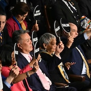 Des gens tiennent de petites pancartes qui portent le mot « faux » en anglais.