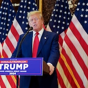 L'ancien président américain Donald Trump tient une conférence de presse devant des drapeaux américains. 