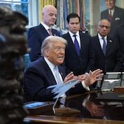 Assis dans le bureau ovale, Donald Trump, entour&eacute; notamment de certains de ses collaborateurs, parle en regardant devant lui.