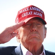 Donald Trump, qui porte une casquette avec son slogan « Rendons sa splendeur à l'Amérique », effectue un salut militaire.