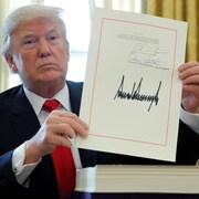 Donald Trump montre sa signature sur le document de la réforme de la fiscalité aux États-Unis.