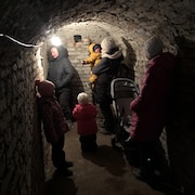 Un tunnel éclairé par une lampe, où s'abritent des adultes et des enfants.