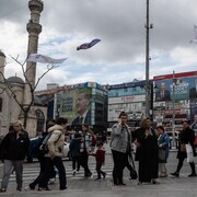 Des gens marchent sous des affiches du président sortant, Recep Tayyip Erdogan, et du principal candidat d'opposition, Kemal Kiliçdaroglu, à Istanbul.