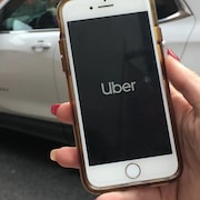 Une femme tient un téléphone intelligent sur lequel l'application d'Uber est en marche.