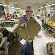 Une femme dans une usine tenant un gilet pare-balles.