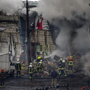 Des pompiers et des secouristes près d'un bâtiment touché par un missile dans le centre de Kyiv le 23 novembre 2022 à Kyiv.