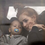 Une femme tient son bébé dans un bus alors qu'ils quittent Kiev, en Ukraine, le jeudi 24 février 2022. 