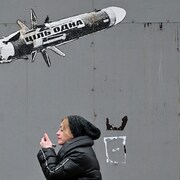 Une femme passe devant un graffiti à Kiev qui montre un missile antichar pris pour cible.