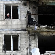 Un résident regarde par la fenêtre de son appartement dans un immeuble résidentiel de plusieurs étages.