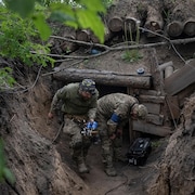 Deux soldats ukrainiens se trouvent dans un fossé, l'un transporte un drone.