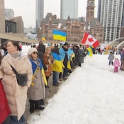 Des gens tiennent des drapeaux du Canada et de l'Ukraine.