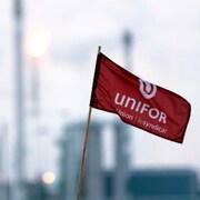 Un drapeau d'Unifor en avant-plan avec les installations de la raffinerie Co-op de Regina en arrière-plan.