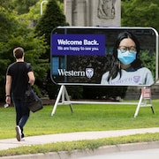 Une personne devant une annonce de l'Université Western.