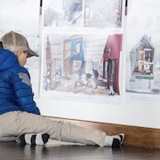 Un garçon regarde une photo avec des rendus 3D d'architecture. 