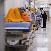 Une ambulancière parle à un patient sur une civière dans le corridor de l'urgence.