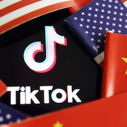 Le logo de TikTok entre des drapeaux chinois et américains.