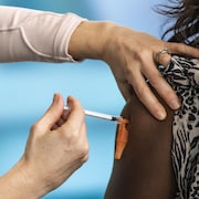 Une personne reçoit une dose de vaccin contre la COVID-19 dans le bras.