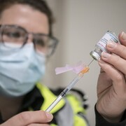 Une ambulancière remplit une seringue d'une dose du vaccin de Moderna.